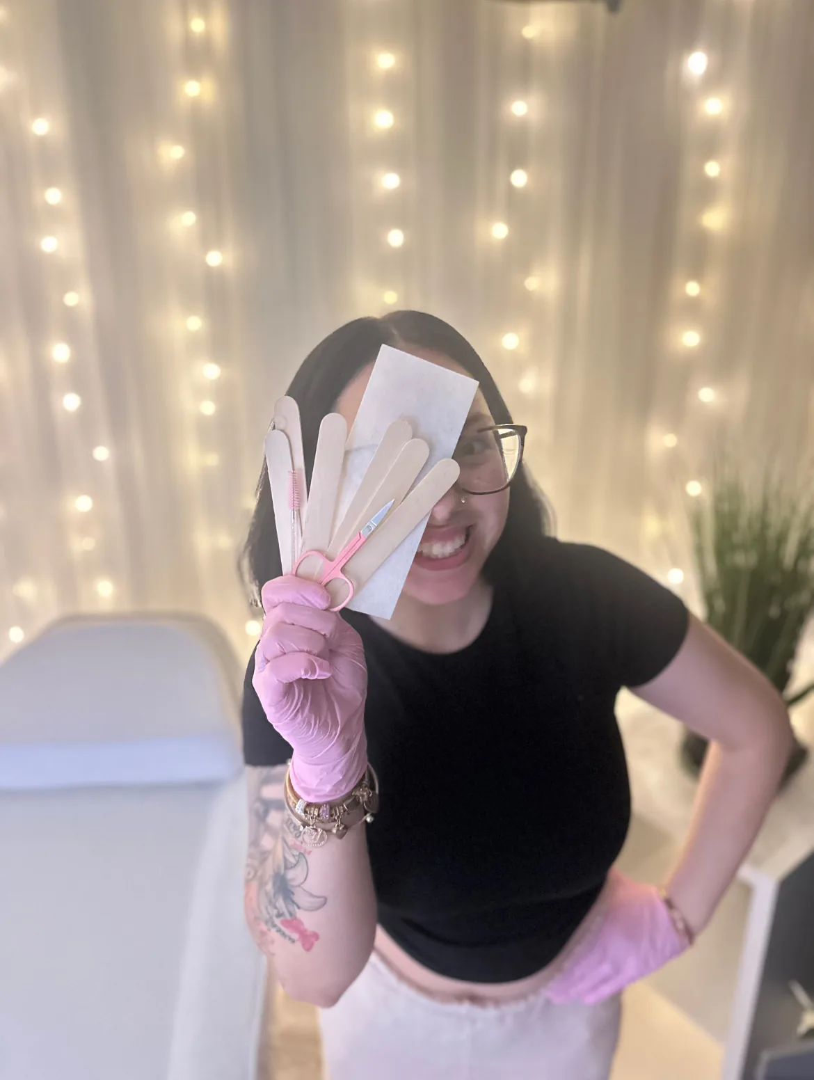 Makayla Simbra, aesthetician at Smooth Skin Spa, smiling and holding wax spatulas in the treatment room